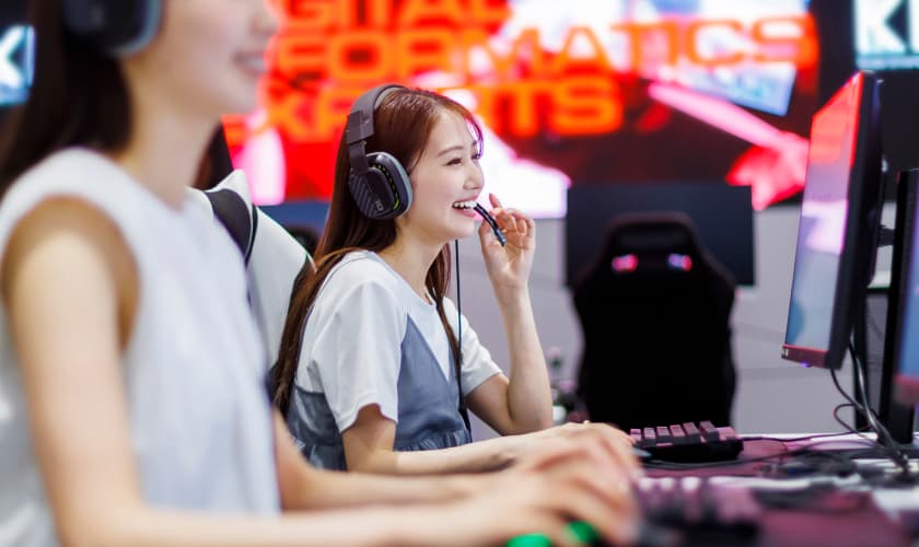 ヘッドセットを着けてパソコンゲームをする女性